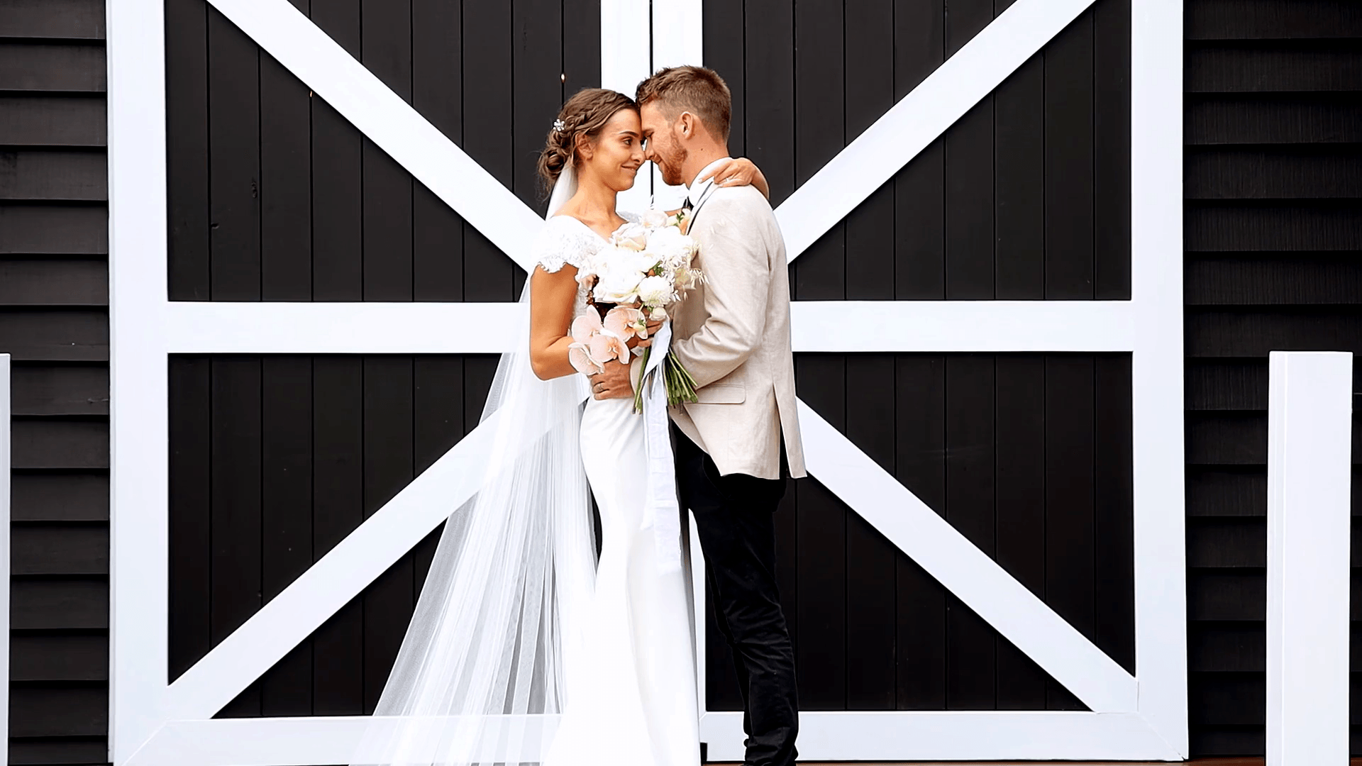 a bride and groom are posing for a picture in front of a barn door .