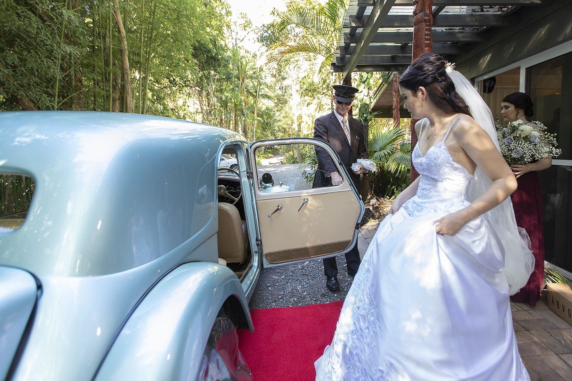 a bride and groom are getting out of a car on a red carpet .