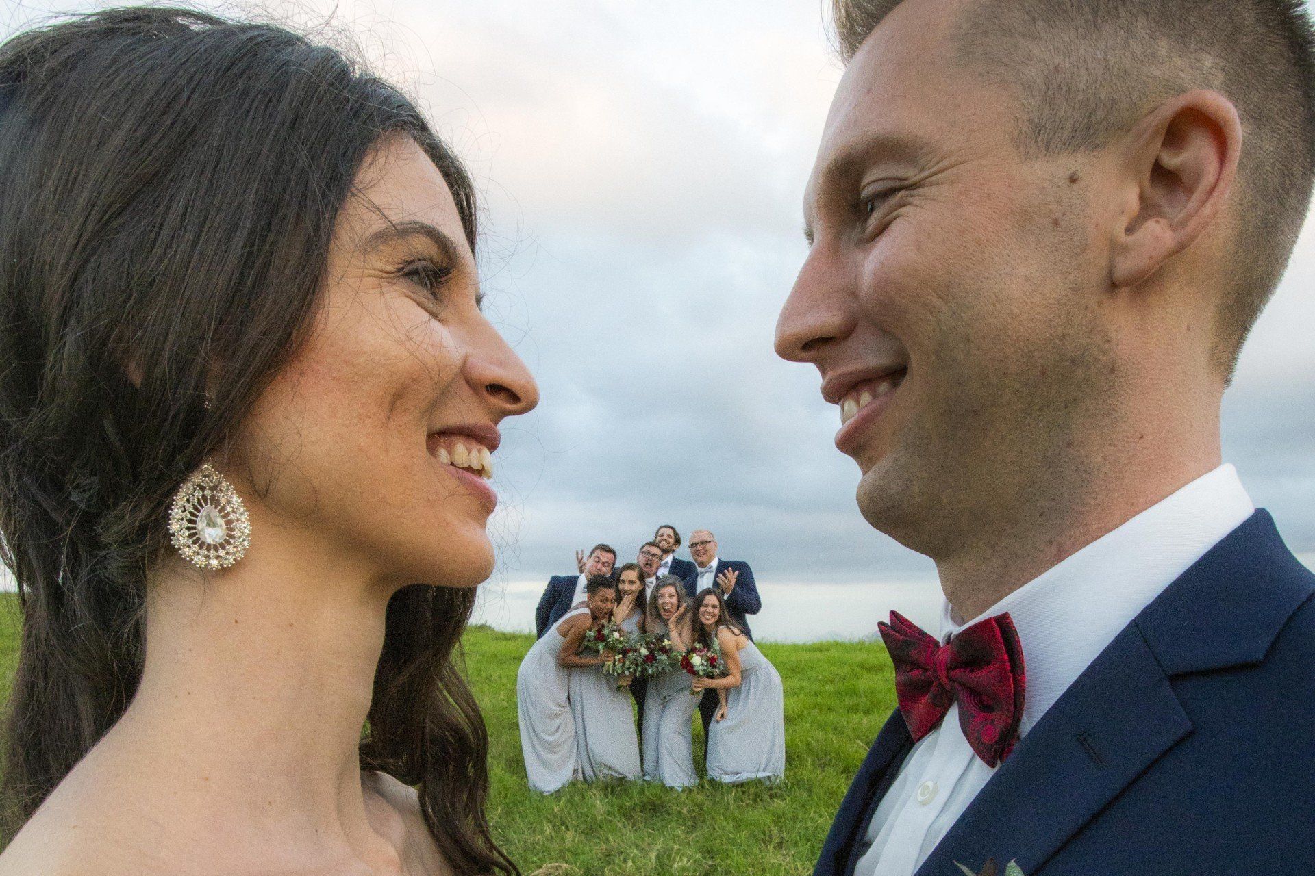 a bride and groom are looking at each other in front of their wedding party .