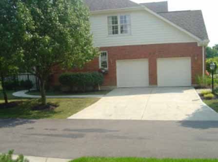 A large brick house with two garage doors and a concrete driveway.