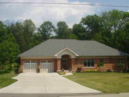 A brick house with a gray roof and white garage doors