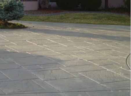 A concrete driveway with a tree in the background and a table in the foreground.