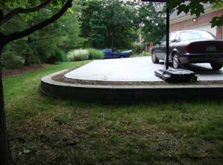 A car is parked in a driveway next to a tree.
