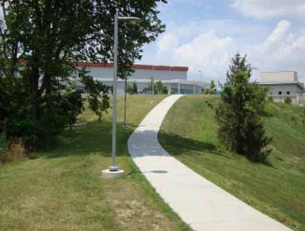 A concrete walkway going up a grassy hill.
