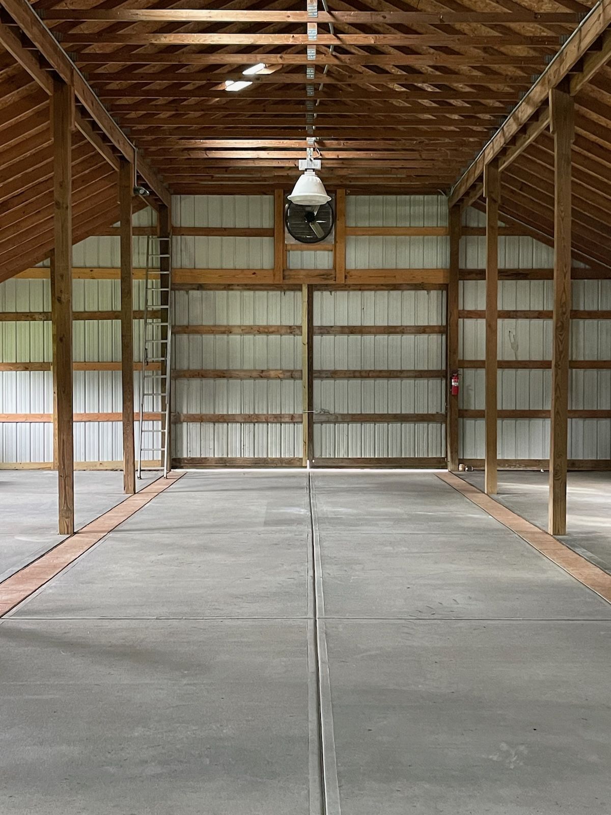 A large empty barn with a ceiling fan hanging from the ceiling.