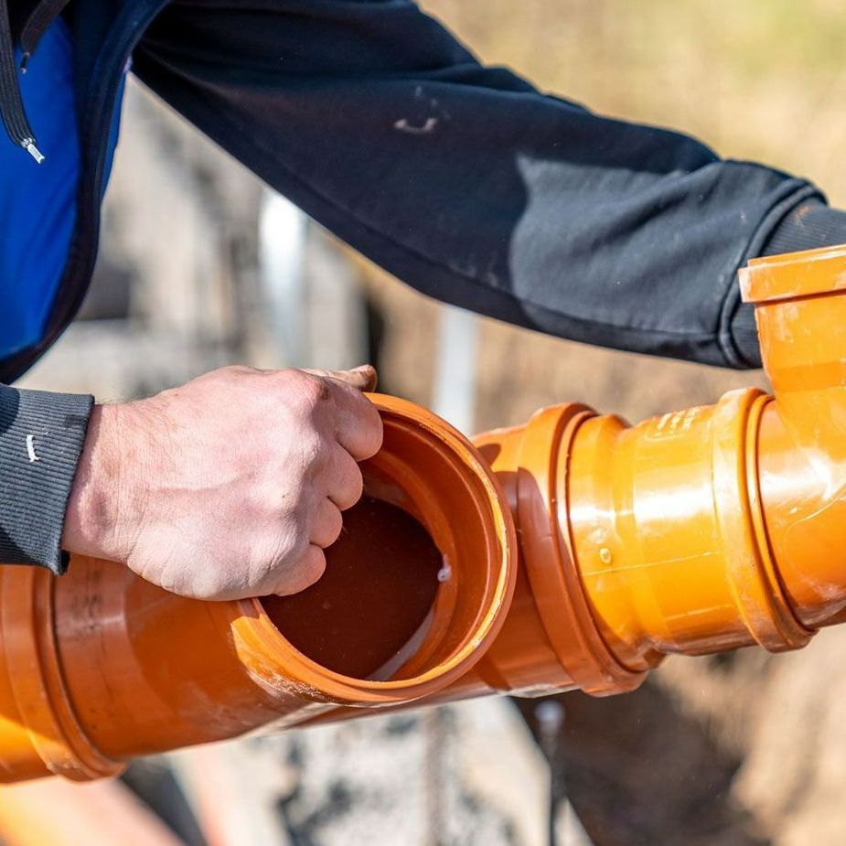 A man is fixing a pipe with his hands.