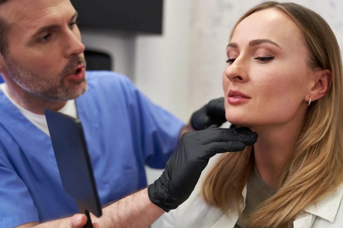 A doctor is examining a woman 's neck with a mirror.