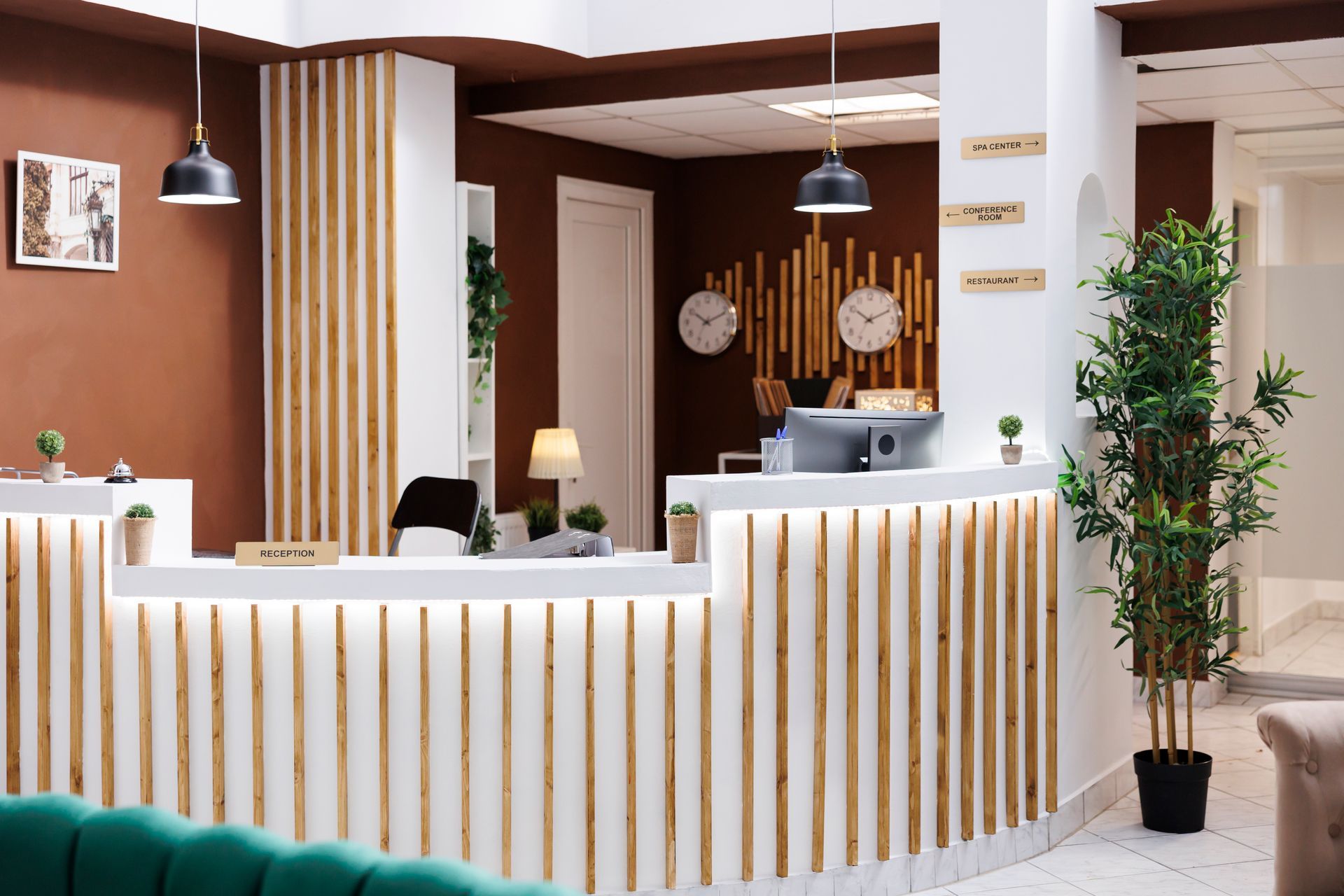 a reception area in a hotel with a green couch and a plant .