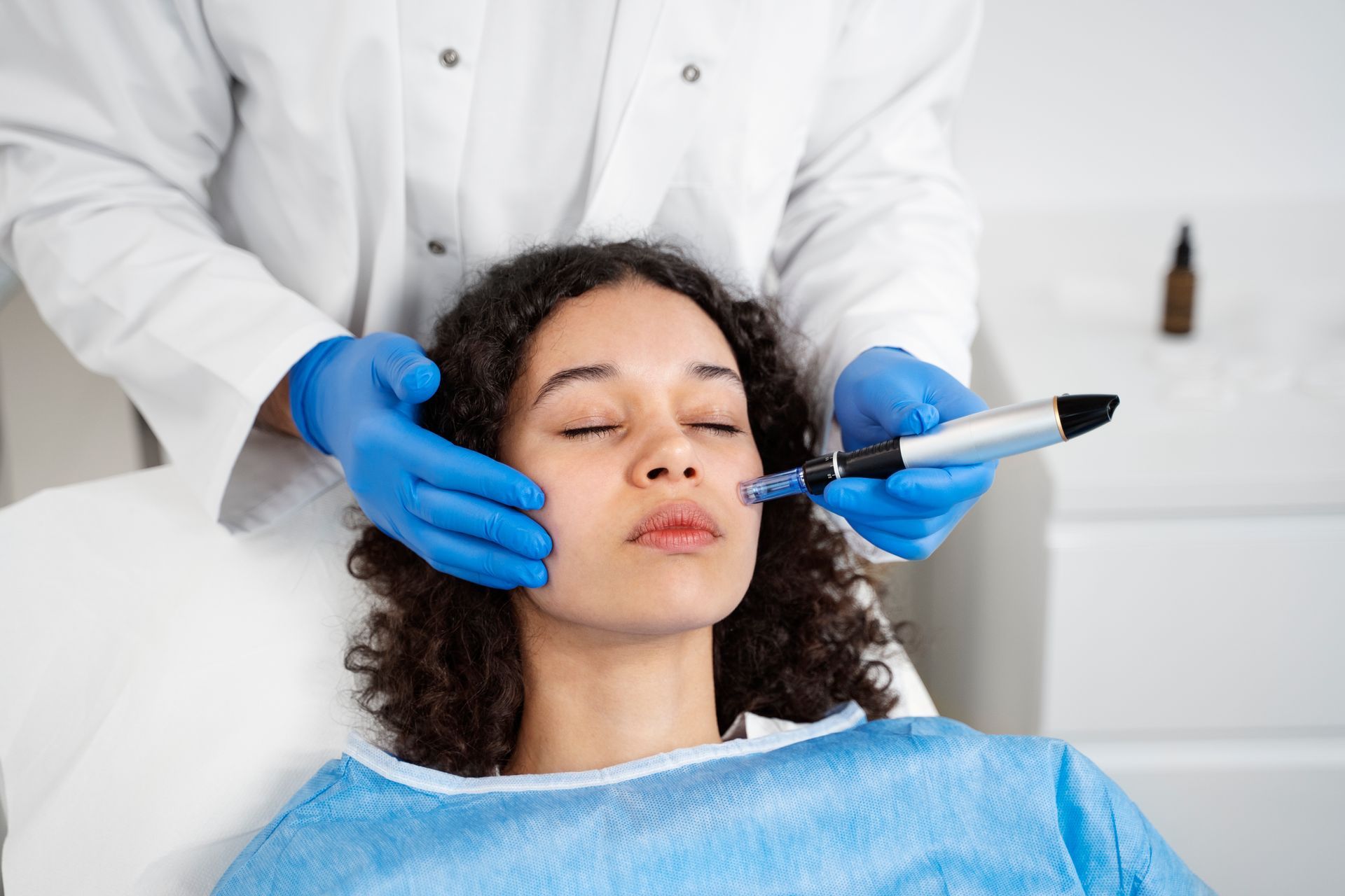 Medical professional using gloved hands and a syringe on a patient’s face in a clinic setting
