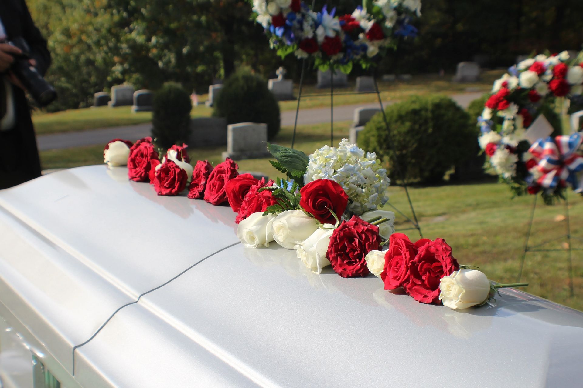 a white coffin with red white and blue flowers on it