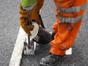 Man pouring paint into line marker on the road