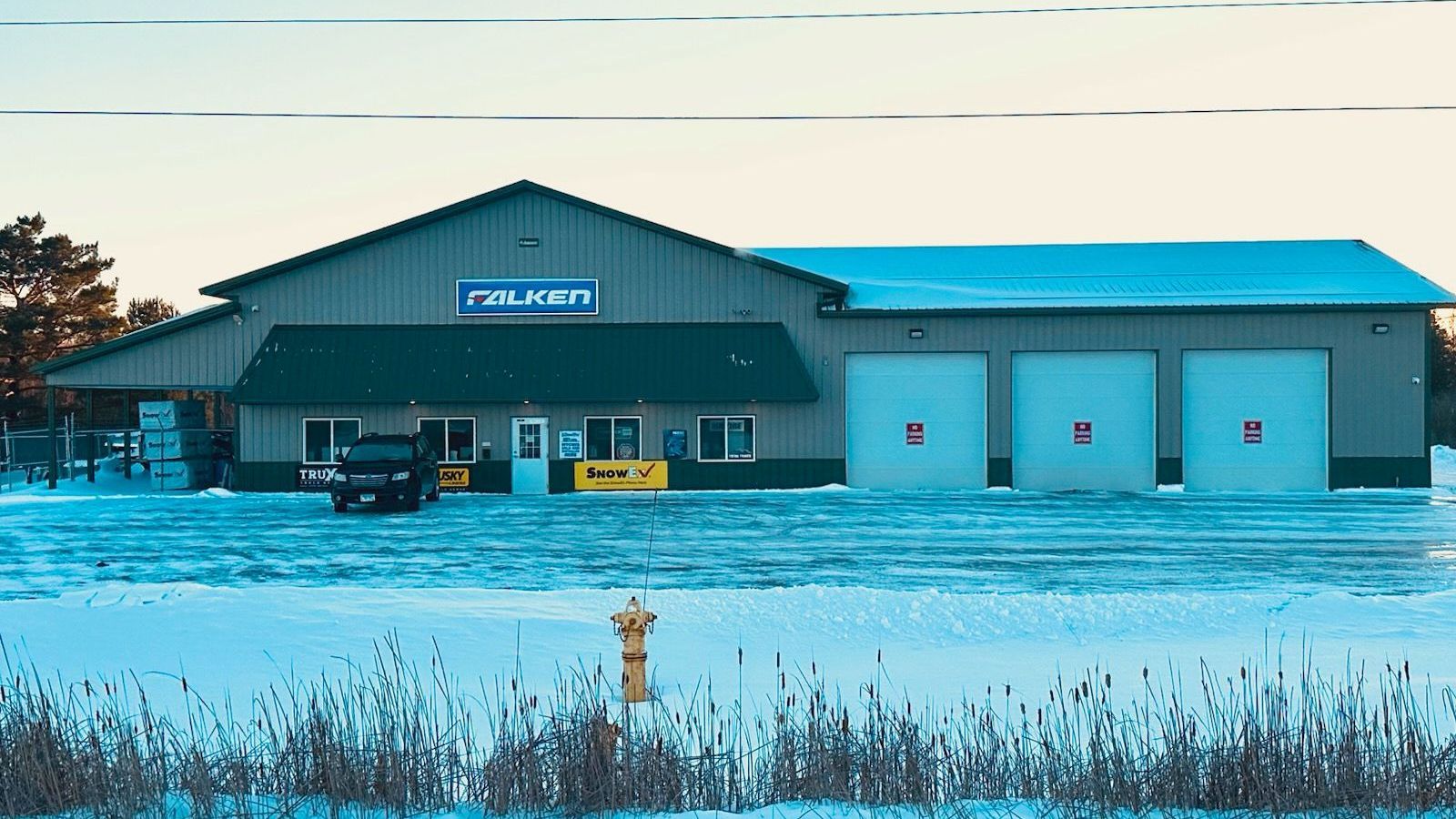 Snowy building with three garage doors. 