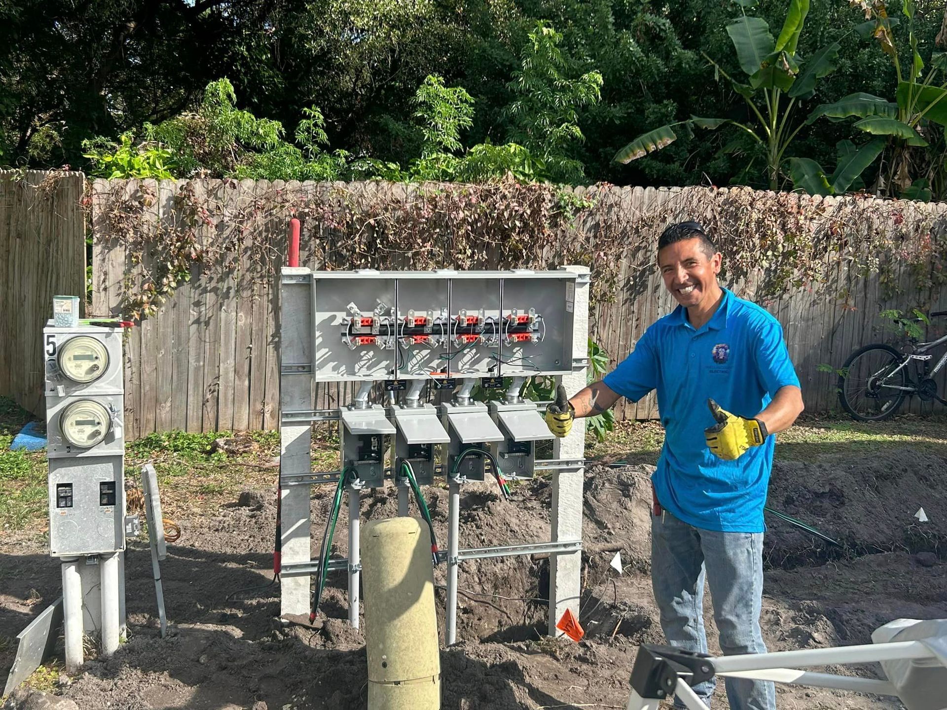 A Man in A Blue Shirt Is Standing in Front of A Electrical Box — Tarpon Springs, FL — Pinellas County Electric