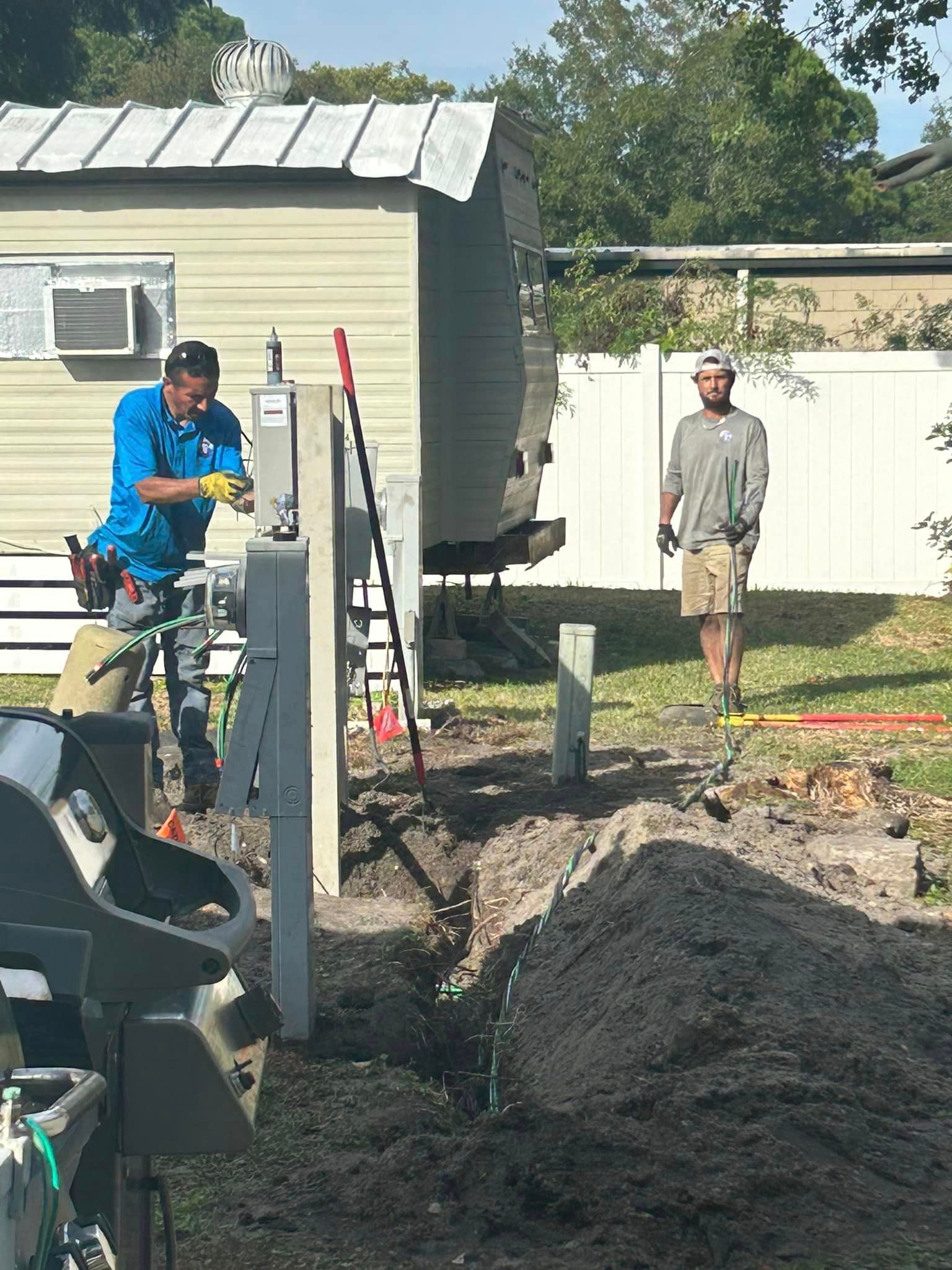 A Man Is Working on A Electrical Box in The Dirt in Front of A Mobile Home — Tarpon Springs, FL — Pinellas County Electric