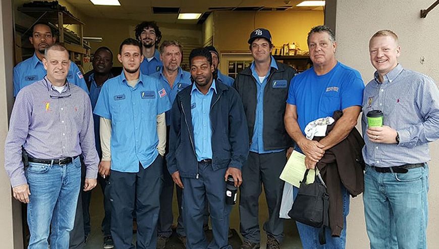 A Group of Men Are Posing for A Picture in Front of A Building — Tarpon Springs, FL — Pinellas County Electric