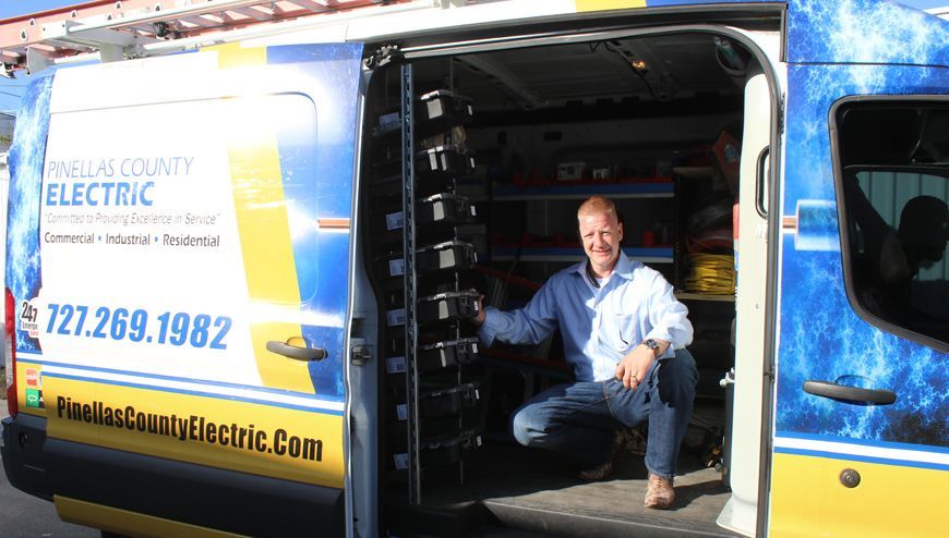 A Man Is Kneeling in The Back of An Electric Van — Tarpon Springs, FL — Pinellas County Electric