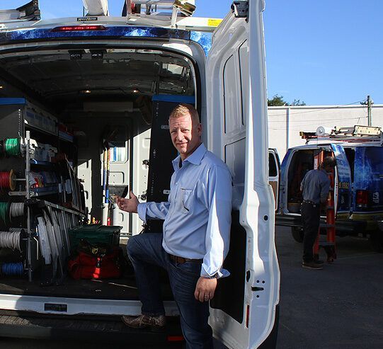 A Man Is Standing in The Back of A Van — Tarpon Springs, FL — Pinellas County Electric