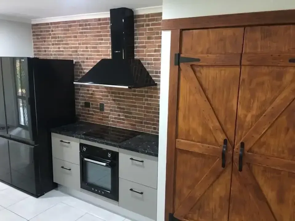A Kitchen with A Brick Wall and A Black Refrigerator — JWB Joinery in Aitkenvale, QLD