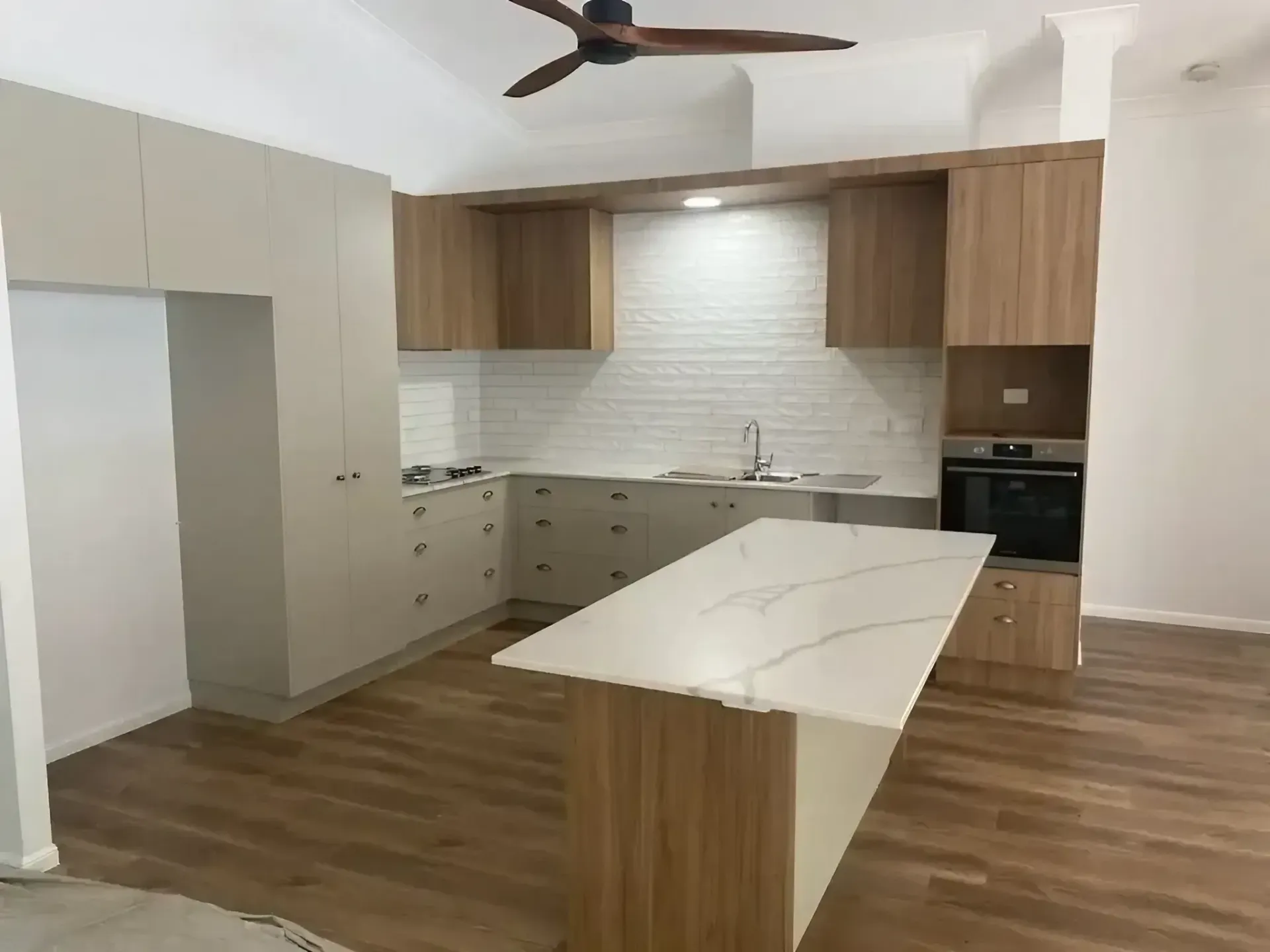 A Kitchen with Wooden Cabinets and A Ceiling Fan — JWB Joinery in Aitkenvale, QLD