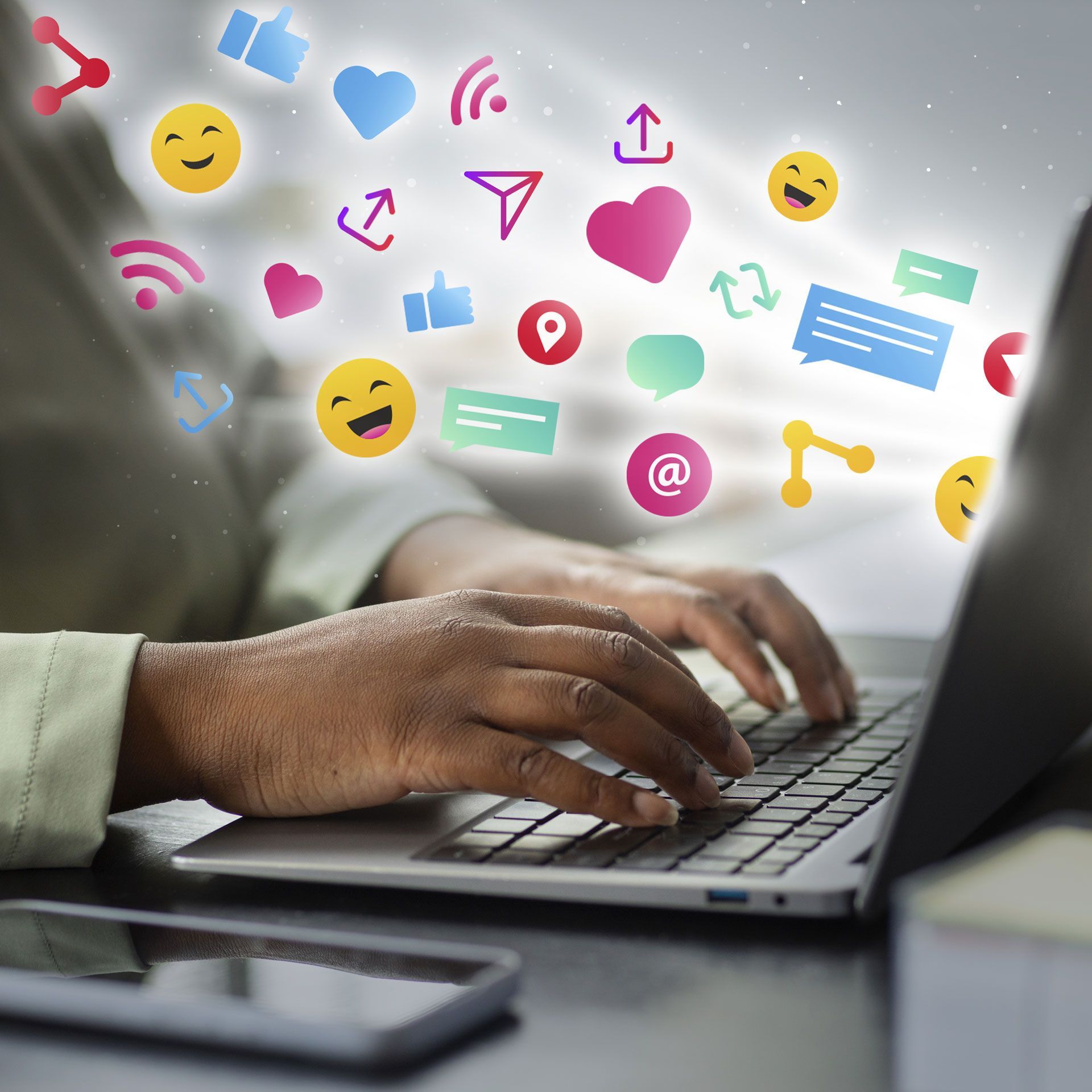 Une personne tape sur un ordinateur portable avec des icônes de réseaux sociaux sortant de l'écran