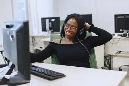Une femme portant des écouteurs est assise à un bureau devant un ordinateur.