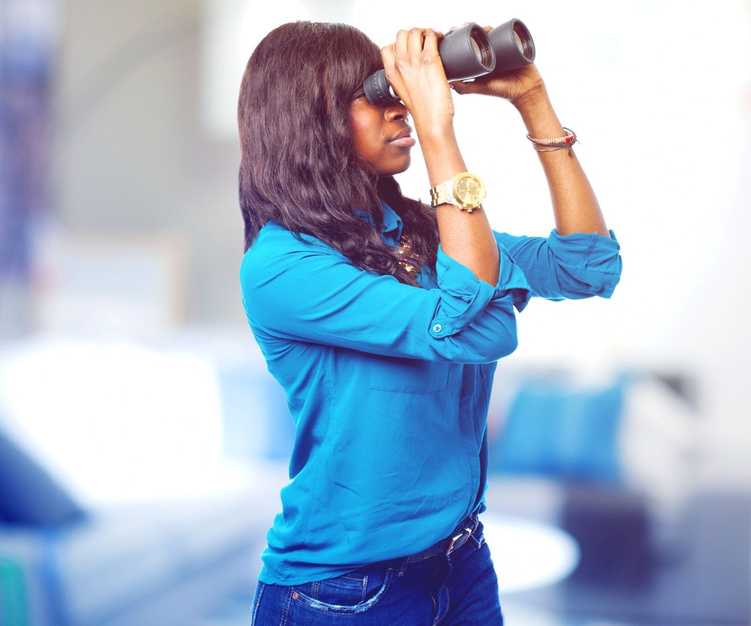 Une femme en chemise bleue regarde à travers des jumelles
