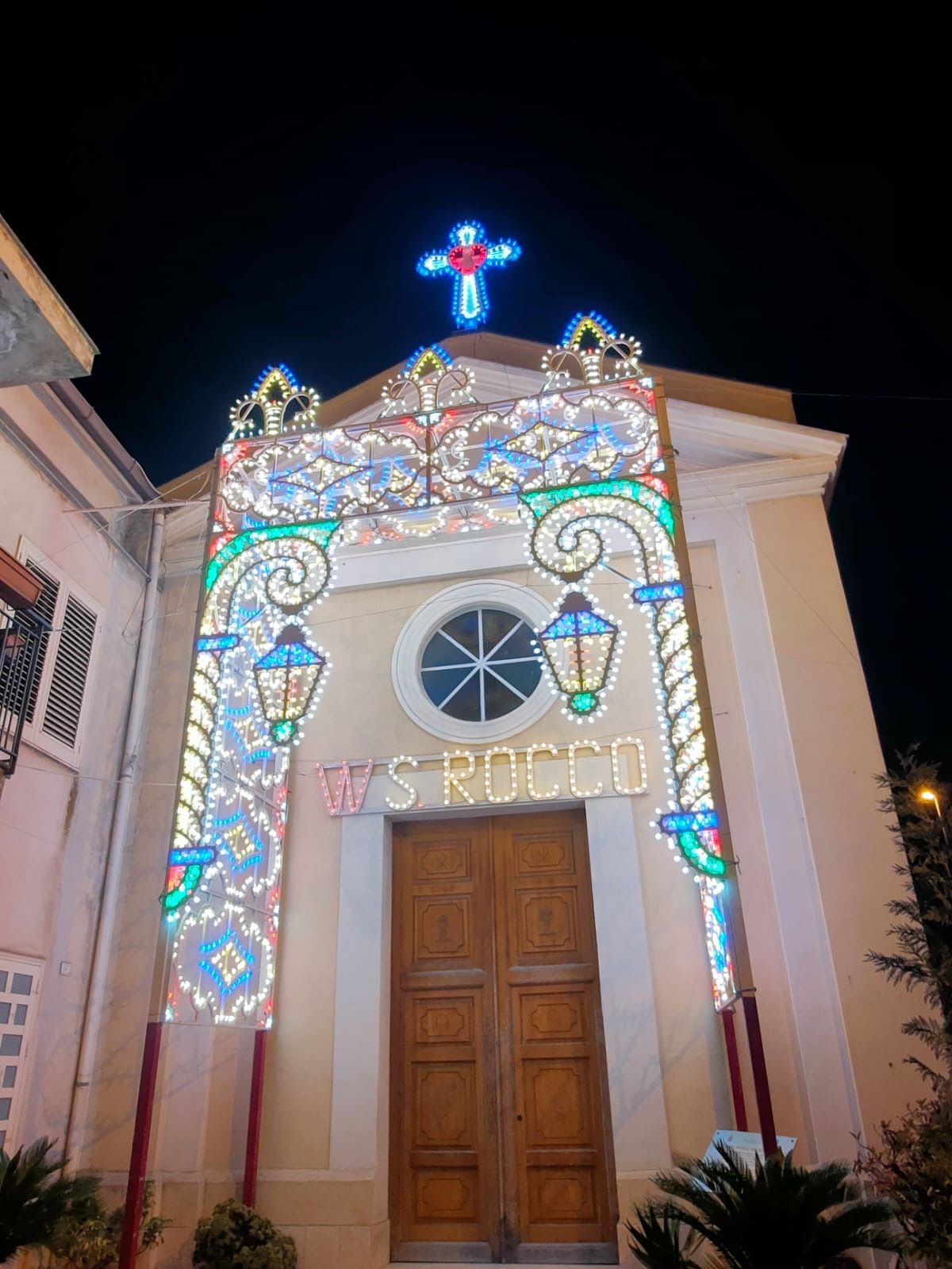 L'ingresso della chiesa è illuminato di notte da colorate luci festive e una croce luminosa.