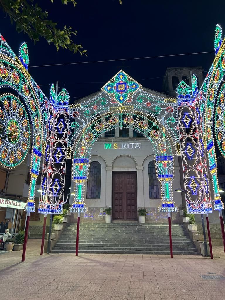 Una facciata di chiesa illuminata a giorno e decorata con colorate luci natalizie di notte