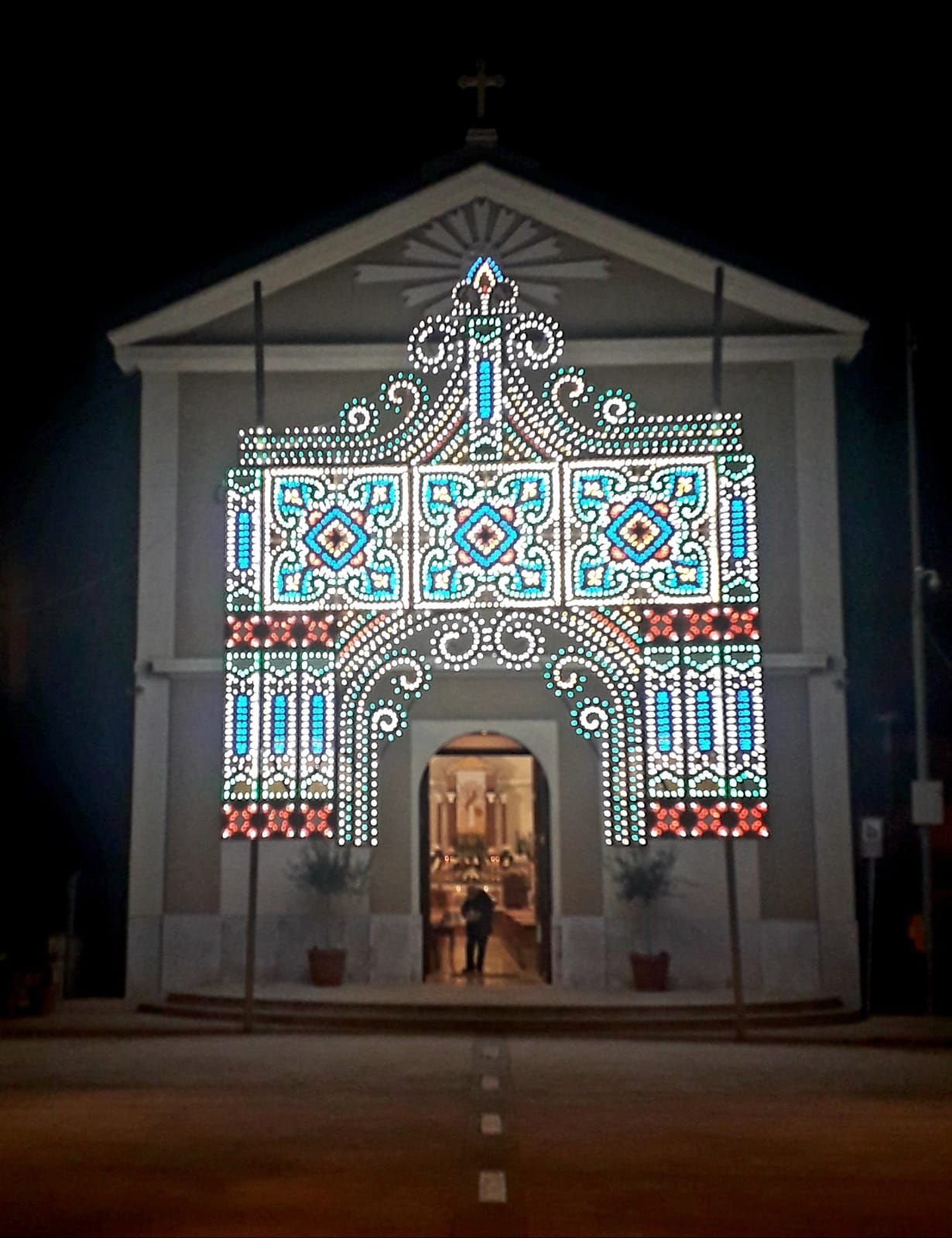 Facciata della chiesa illuminata di notte con luci colorate in stile vetrata, portale luminoso al centro