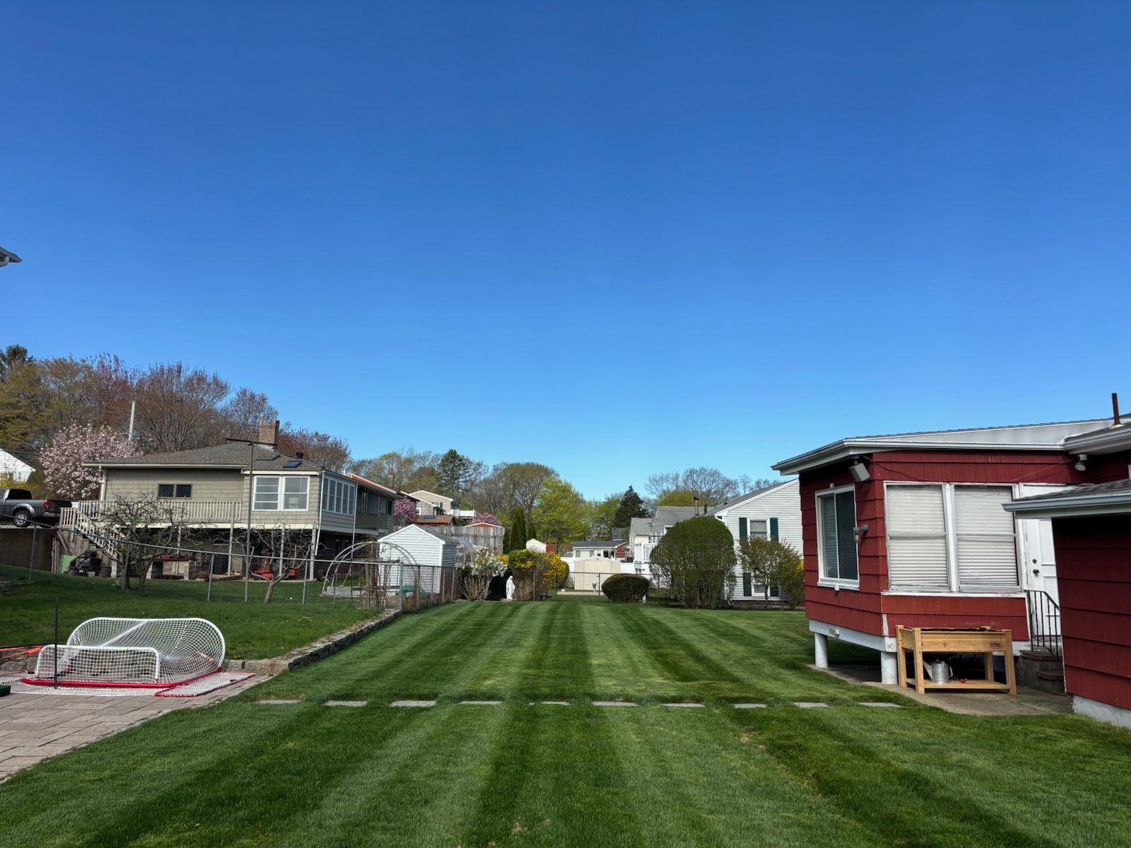 A lush green yard with a red house in the background