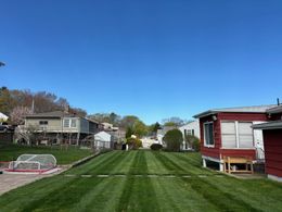 A lush green yard with a red house in the background