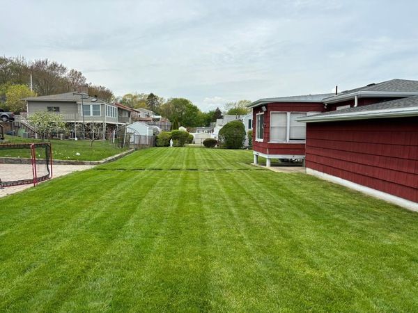 A lush green lawn with a red house in the background.
