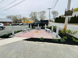 A black truck is parked on the side of the road in a parking lot.