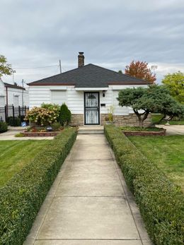 A white house with a black door and a walkway leading to it.