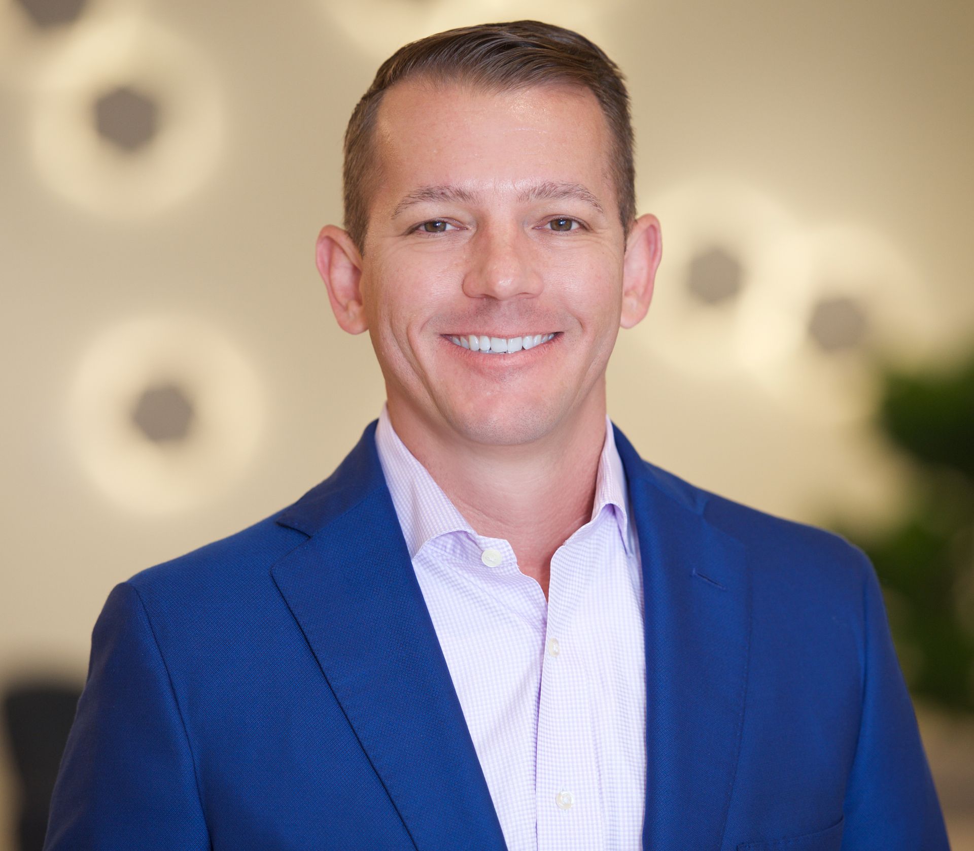 A man in a blue suit and white shirt is smiling for the camera.