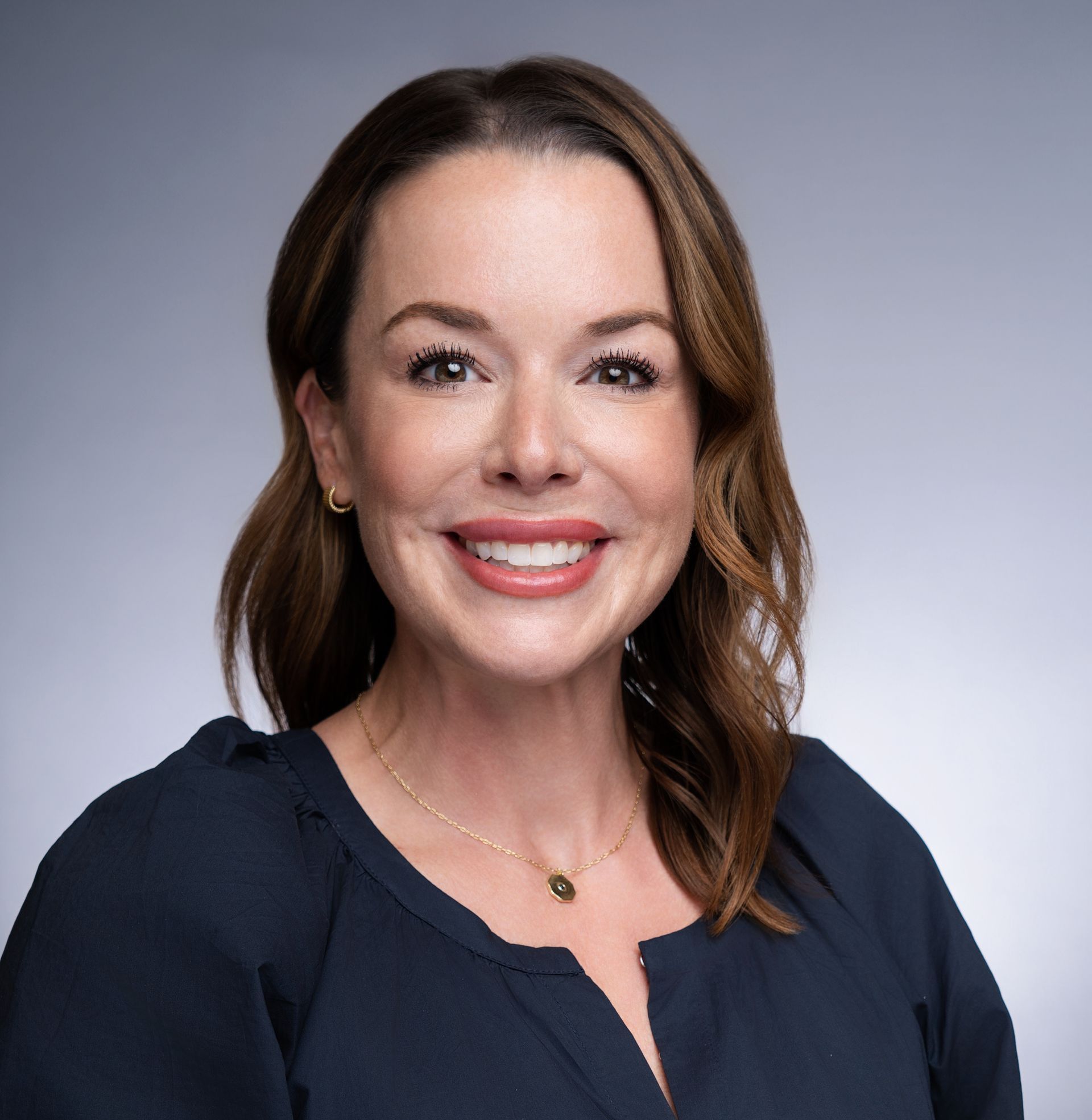 A woman in a blue shirt is smiling for the camera.