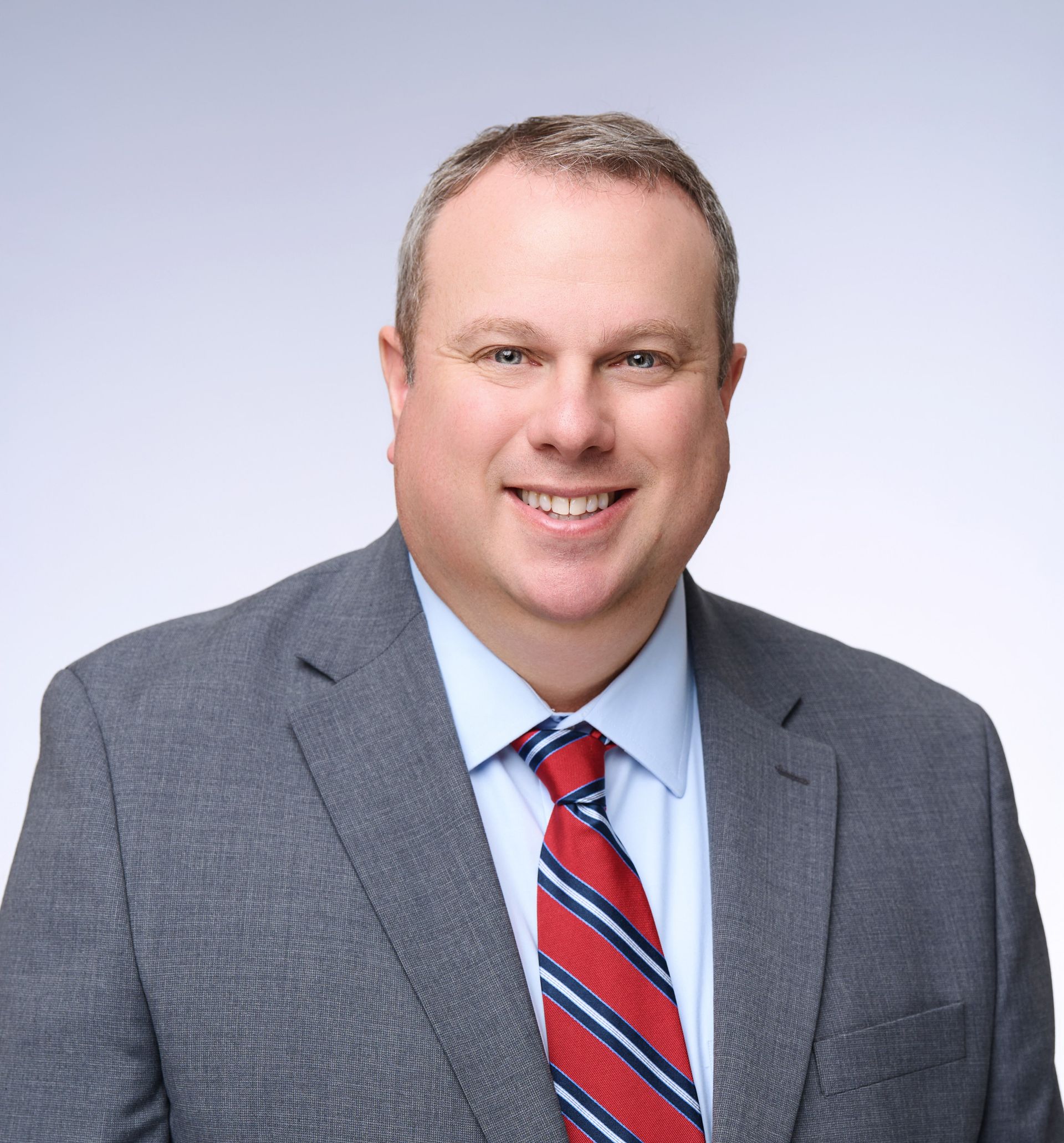 A man in a suit and tie is smiling for the camera