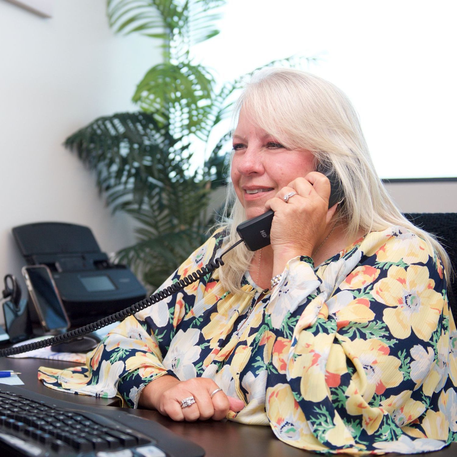 A woman in a floral shirt is talking on a phone