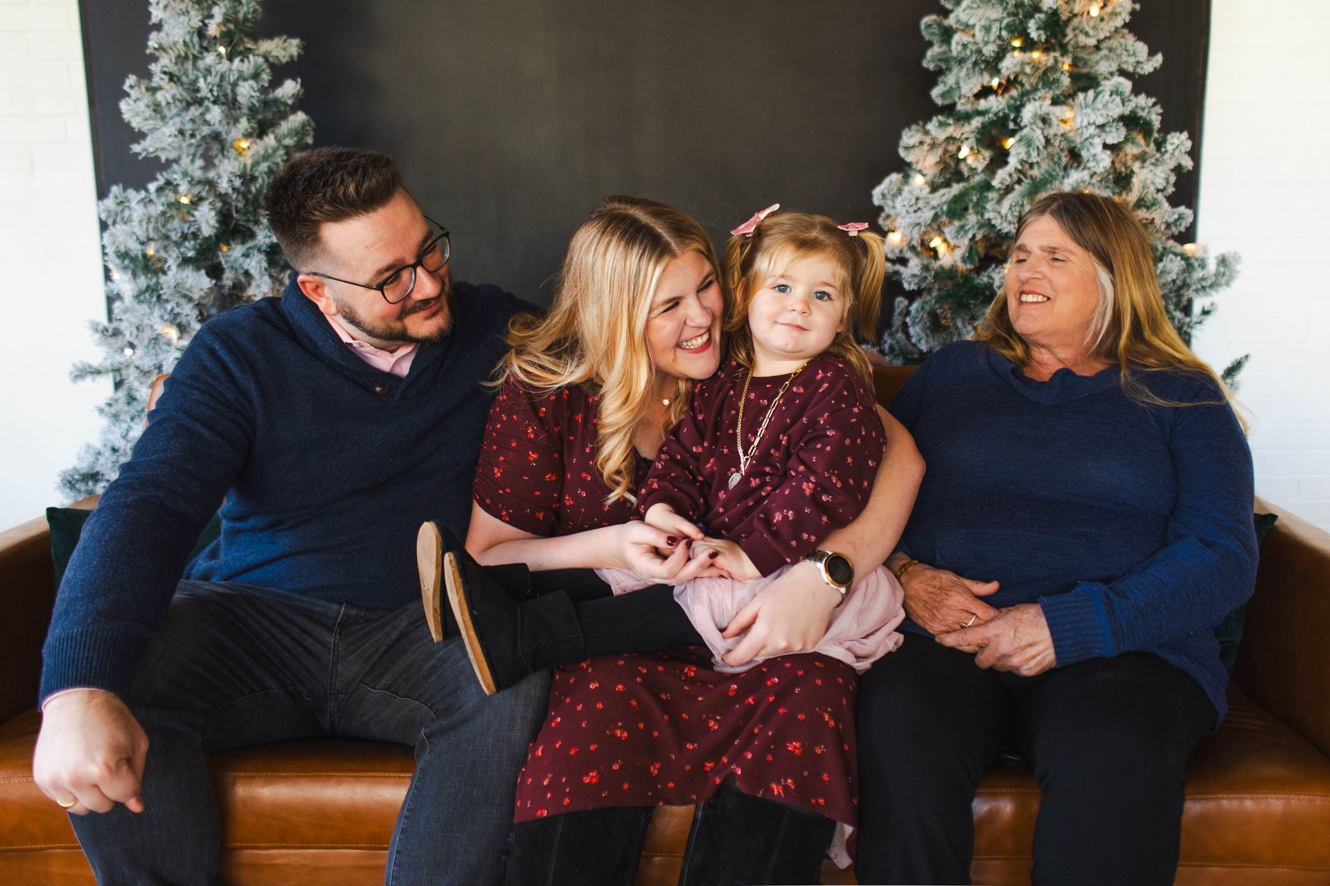 A family is sitting on a couch in front of a christmas tree.