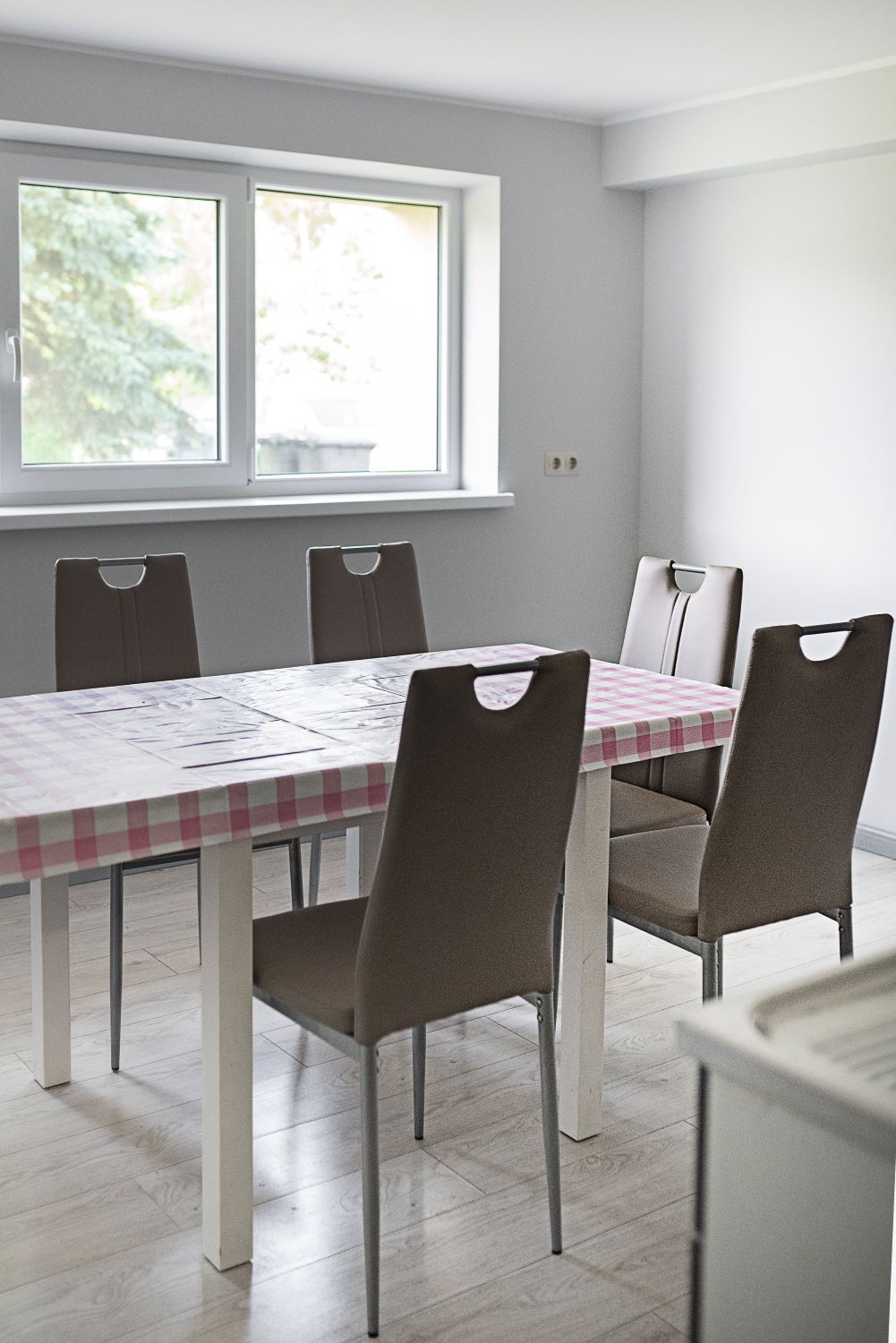 Valgomasis su stalu ir kėdėmis priešais langą.