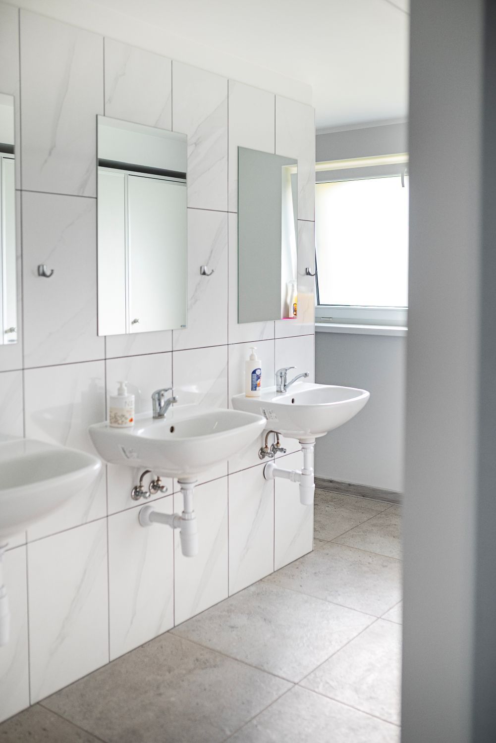 Vonios kambarys su dviem kriauklėmis, veidrodžiu ir langu.