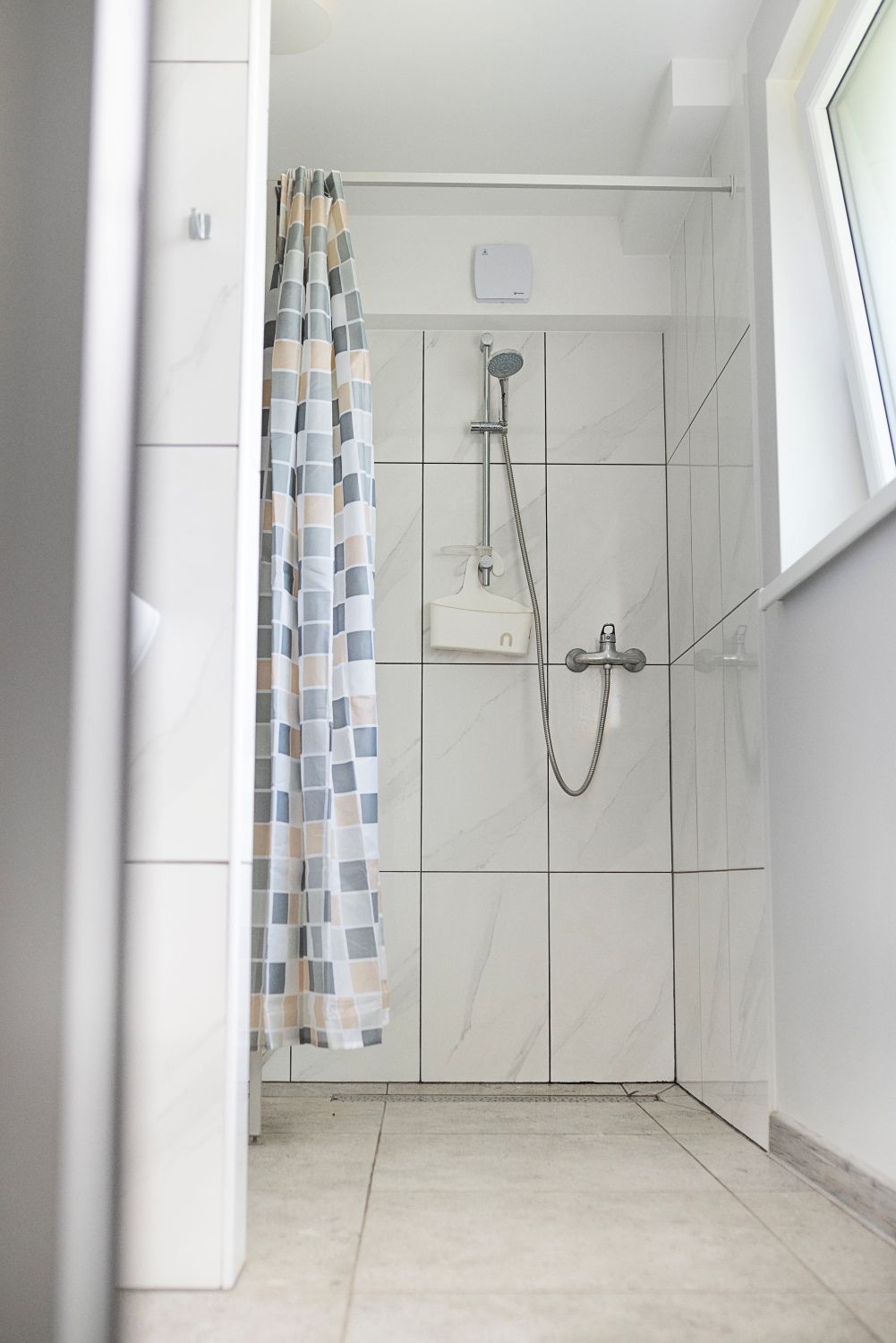 Vonios kambarys su dušo užuolaida ir langu