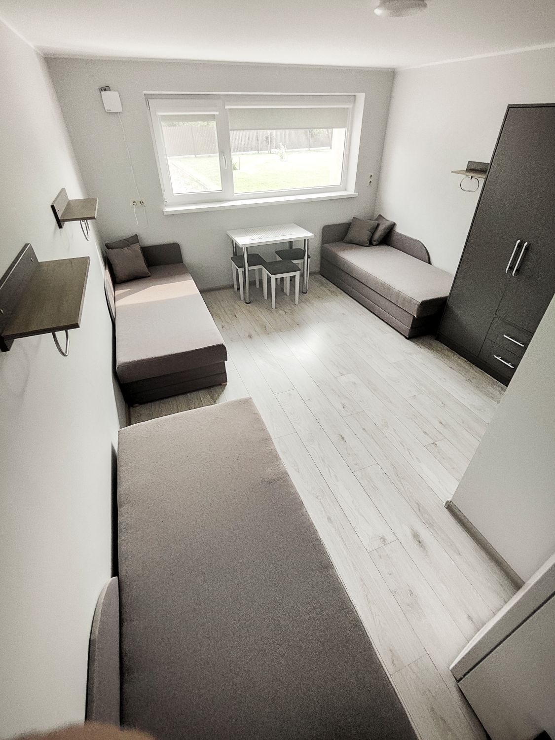 Svetainė su sofa-lova, dviem lovomis, stalu ir kėdėmis.