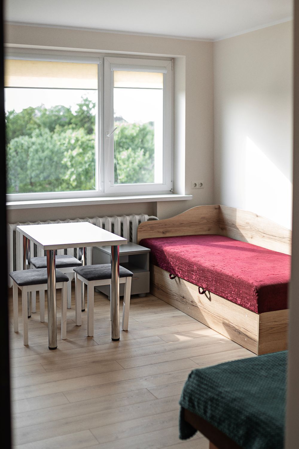 Miegamasis su lova, stalu, kėdėmis ir langu.