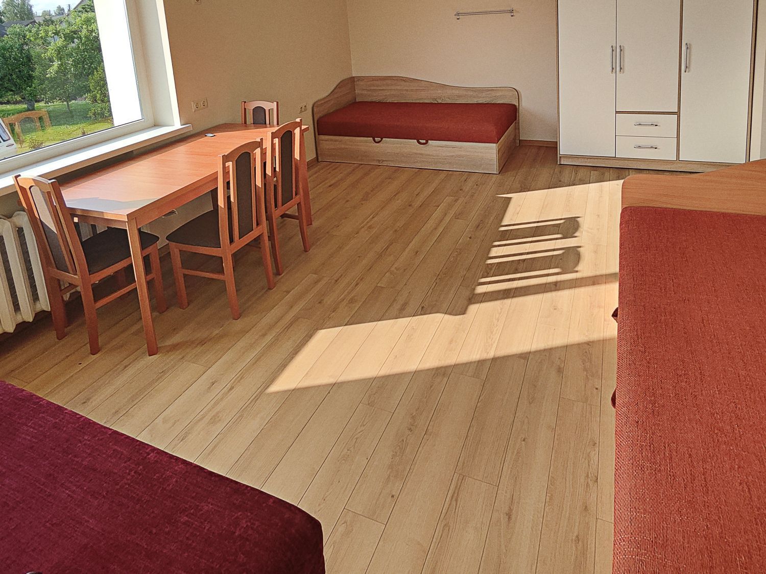 Trivietis kambarys su stalu, kėdėmis.