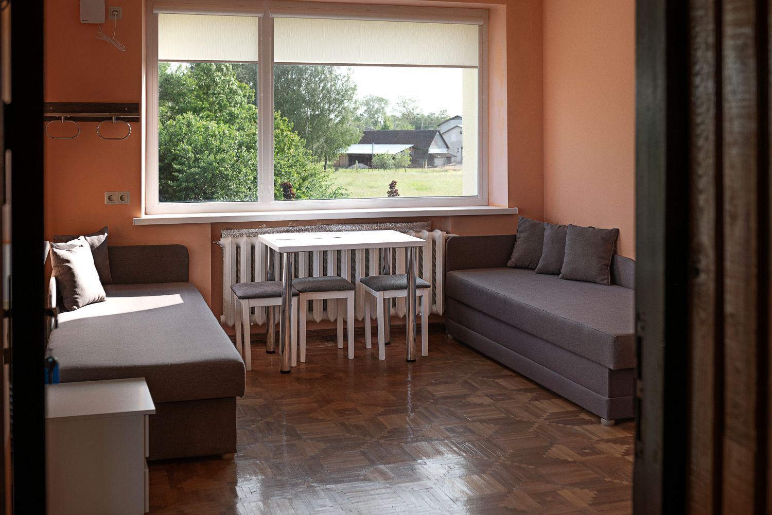 Svetainė su sofa, stalu, kėdėmis ir langu.