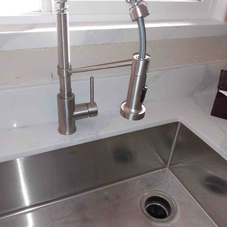 A kitchen sink with a stainless steel faucet