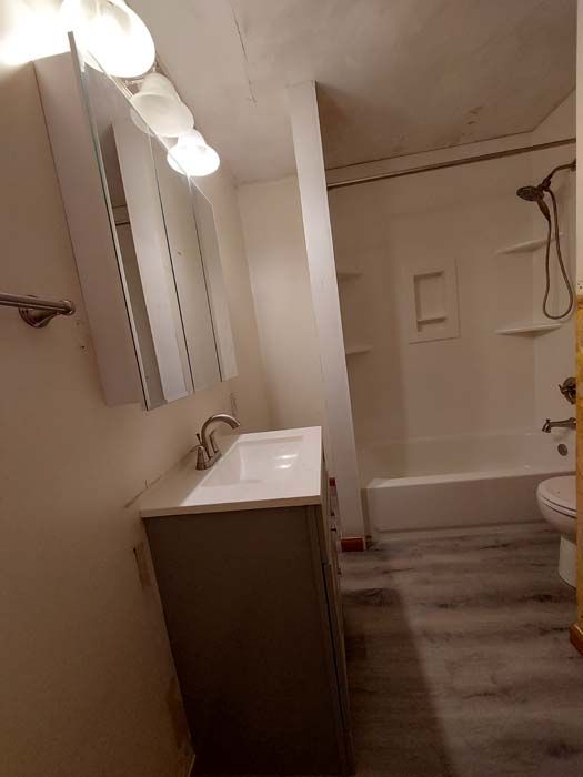 Bathroom with a vanity, shower/tub combo, and gray wood-look flooring.