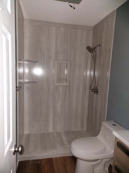 Bathroom with gray shower stall, toilet, and wooden floor.