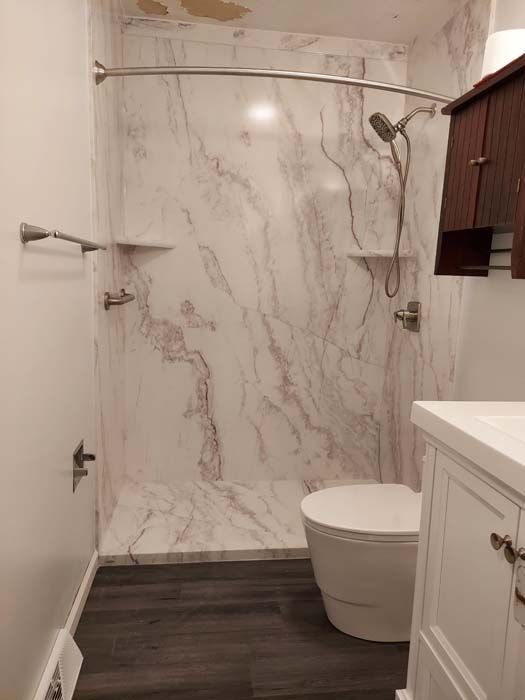 Bathroom with a marble-look shower, toilet, vanity, and dark wood-look flooring.